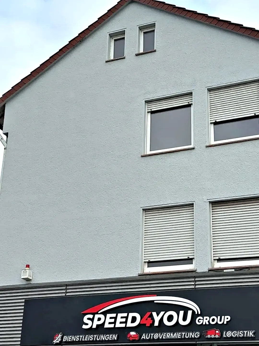 Die Giebelwand an der Eckendorfer Straße vor der Gestaltung: eine graue Putzfläche über dem Speed4you-Firmenschild.